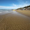 Una spiaggia sabbiosa con mare calmo e colline sullo sfondo.