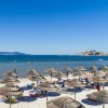 Spiaggia con ombrelloni di paglia e mare blu.