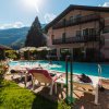 Piscina davanti a edificio rosa, sdraio e sole.