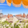 Spiaggia con lettini e ombrelloni arancioni sotto un cielo blu.