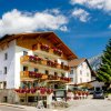 Hotel alpino con balconi fioriti e cielo sereno.