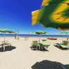 Spiaggia con ombrelloni verdi e gialli, sdraio e mare sullo sfondo.