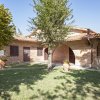 Casa rurale in mattoni con giardino ombreggiato da alberi.