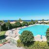 Una grande piscina circondata da alberi e sedie a sdraio, con vista mare.
