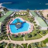 Vista aerea di una piscina con giardini e il mare sullo sfondo.