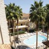 Piscina circondata da palme e edifici in un complesso residenziale.