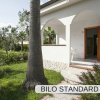 Veranda di una casa bianca con prato e palme.